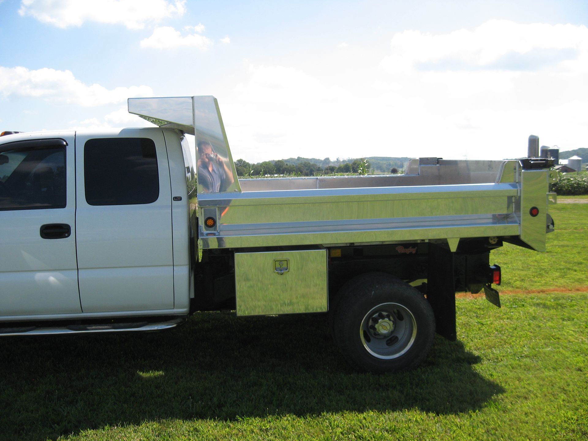 A white dump truck is parked in a grassy field