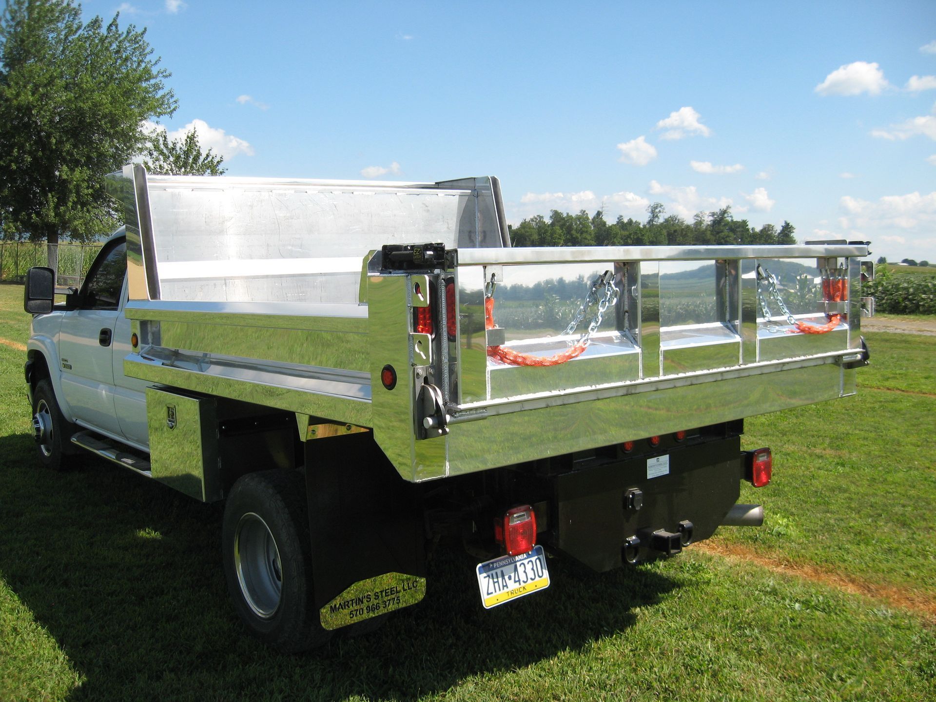 A silver truck is parked in a grassy field