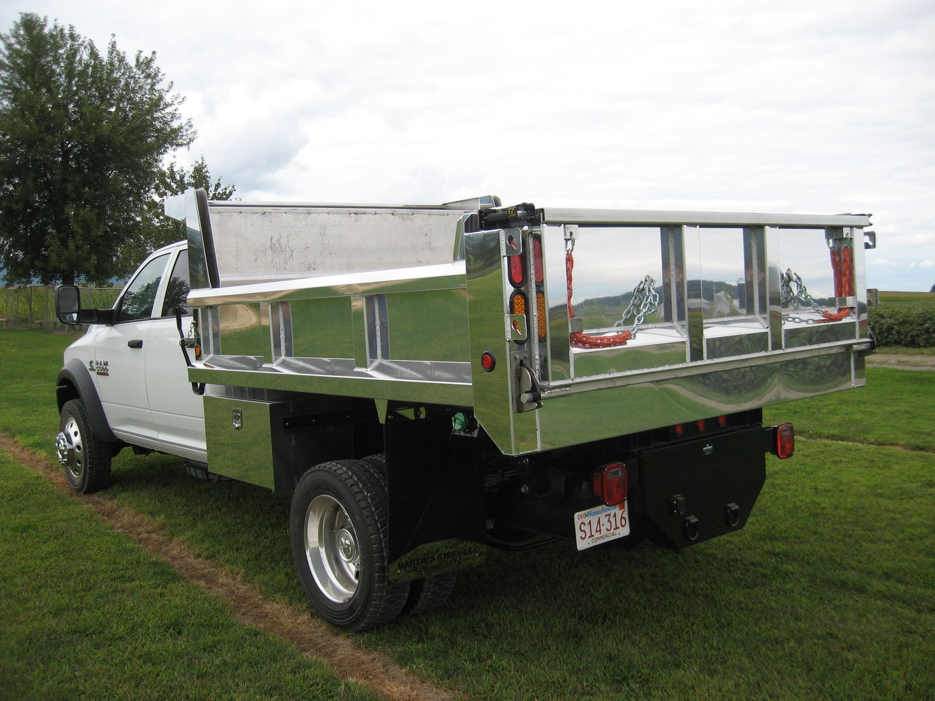A white dump truck is parked in a grassy field.