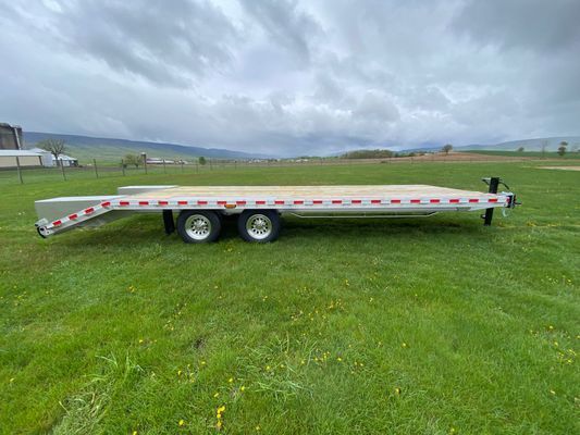 A flatbed trailer is parked in a grassy field.