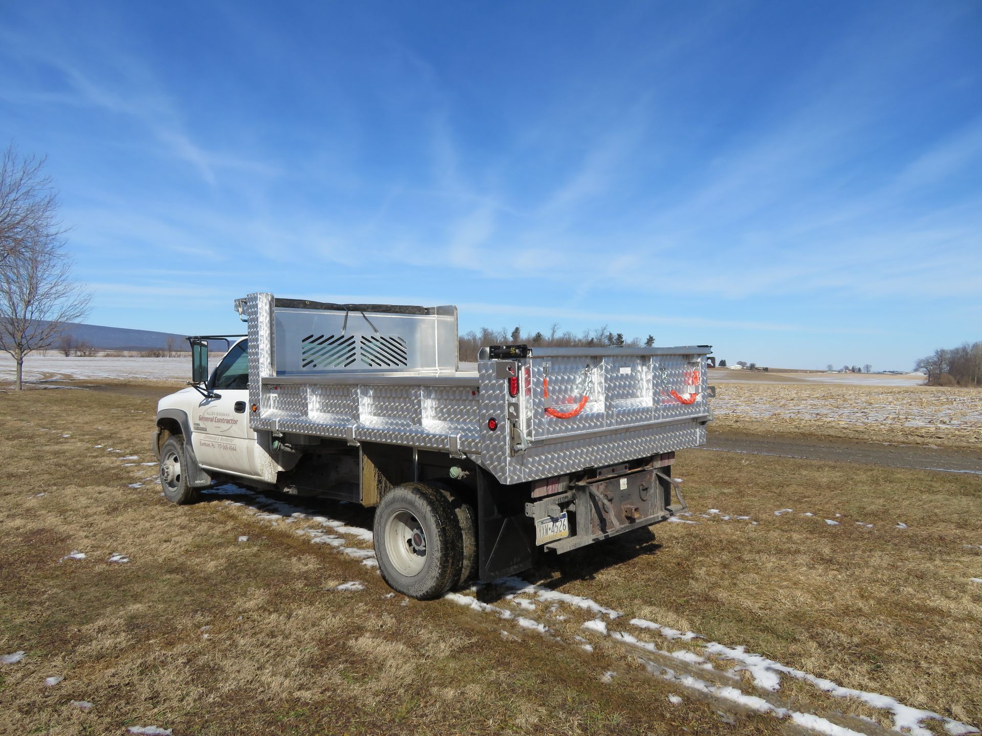 A white dump truck is parked in the middle of a field.