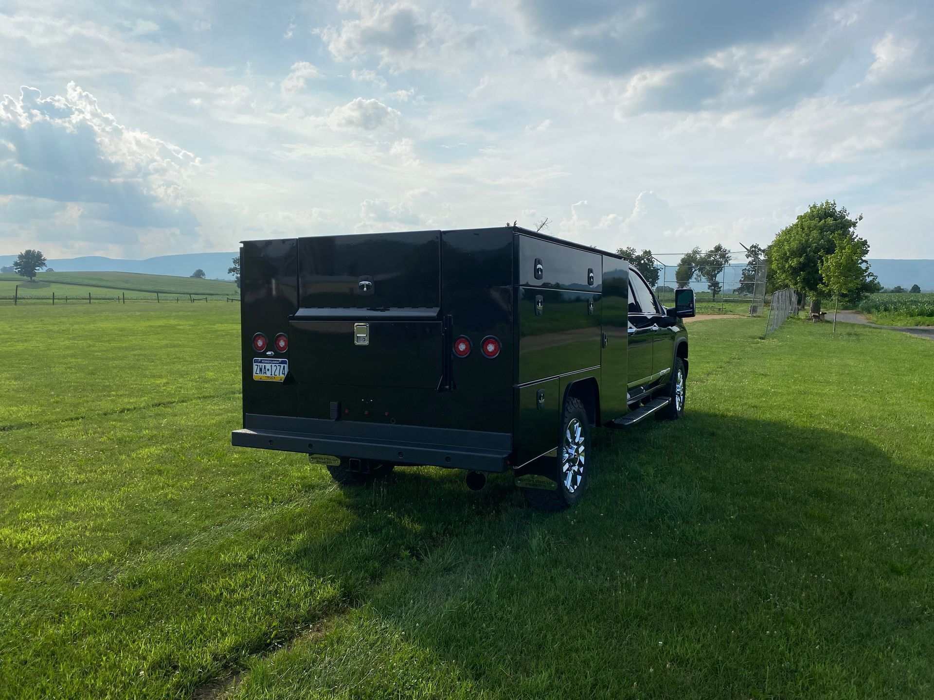 A black truck is parked in a grassy field.