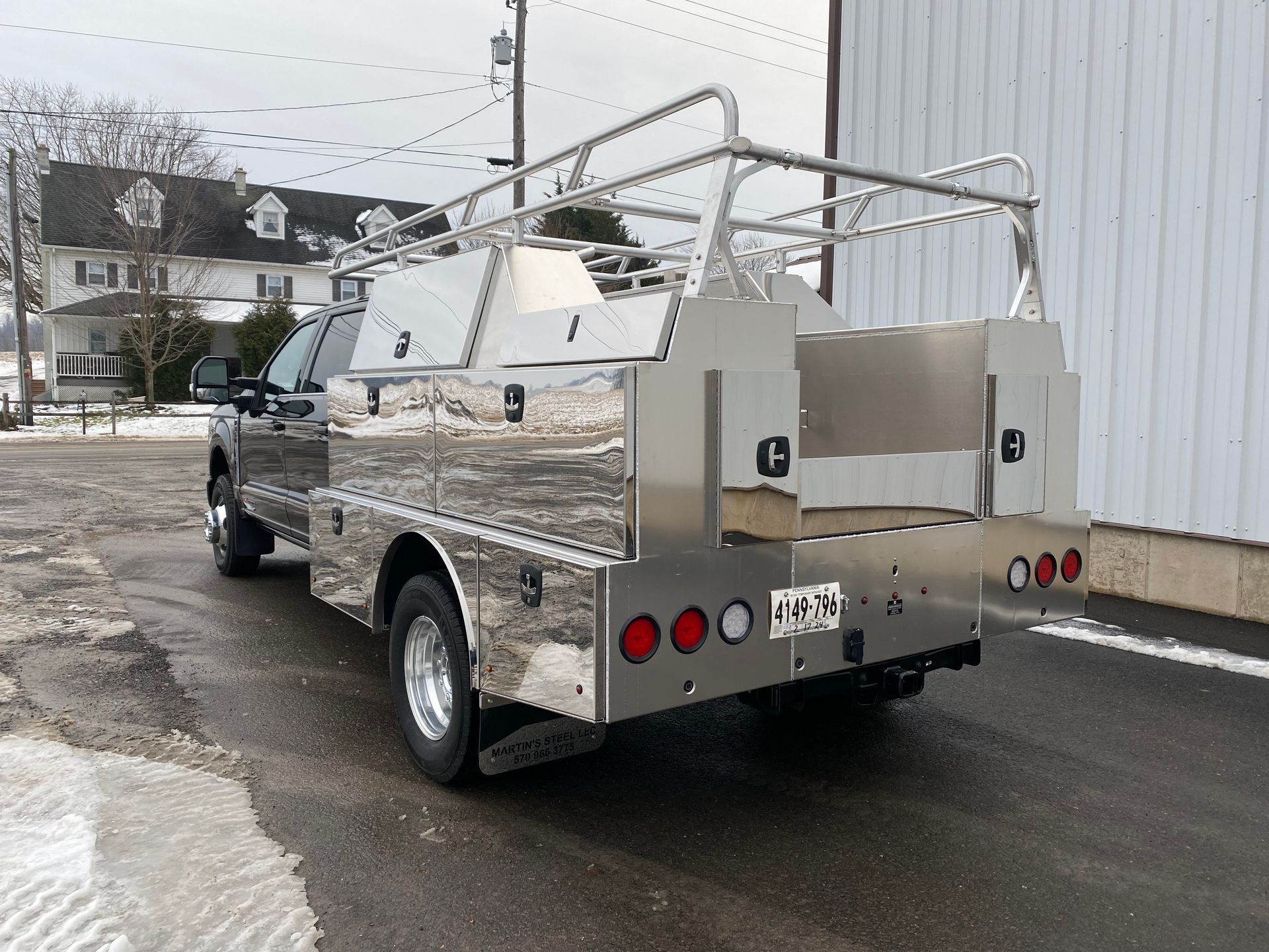 A truck with a stainless steel bed is parked in a parking lot