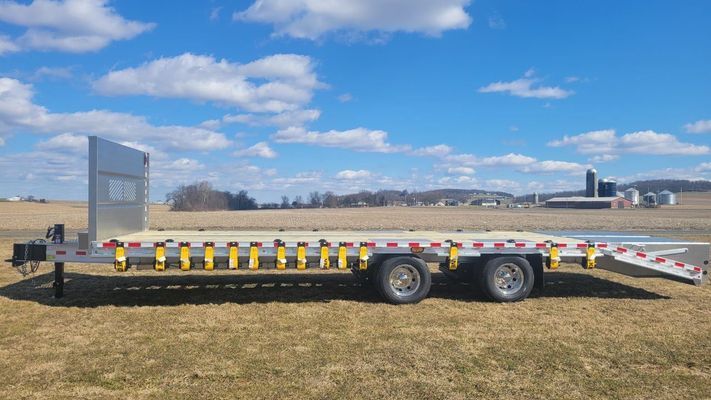 A flatbed trailer is parked in a grassy field.