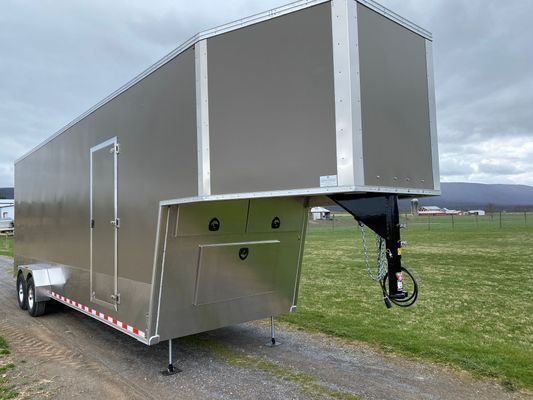 A trailer is parked on the side of a dirt road in a field.