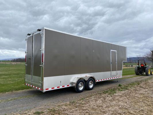 A trailer is parked on the side of a road next to a tractor.