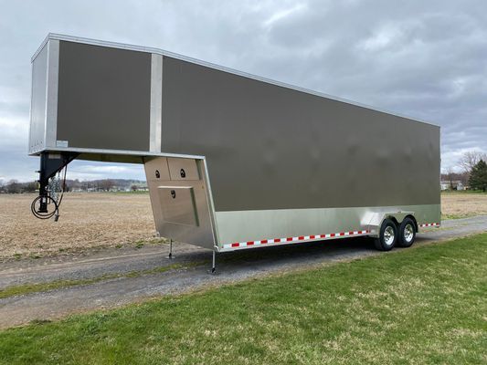 A trailer is parked on the side of a road next to a field.