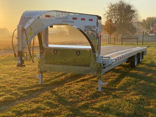 A flatbed trailer is parked in a grassy field.