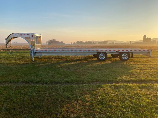 A flatbed trailer is parked in a grassy field.