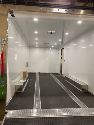 A large empty room with a carpeted floor and a white wall.