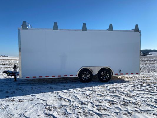 A white trailer is parked in a snowy field.