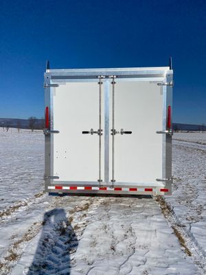 A white trailer is parked in the middle of a snowy field
