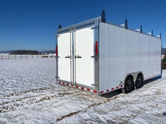 A white trailer is parked in a snowy field.