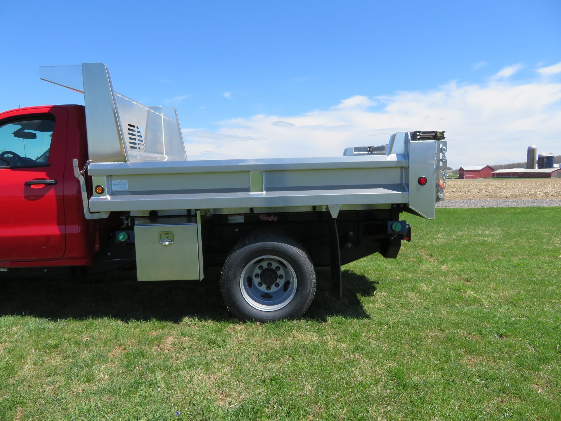 A red dump truck is parked in a grassy field.