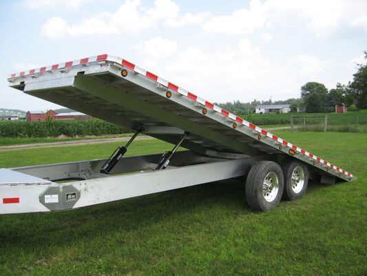 A flatbed trailer is parked in a grassy field