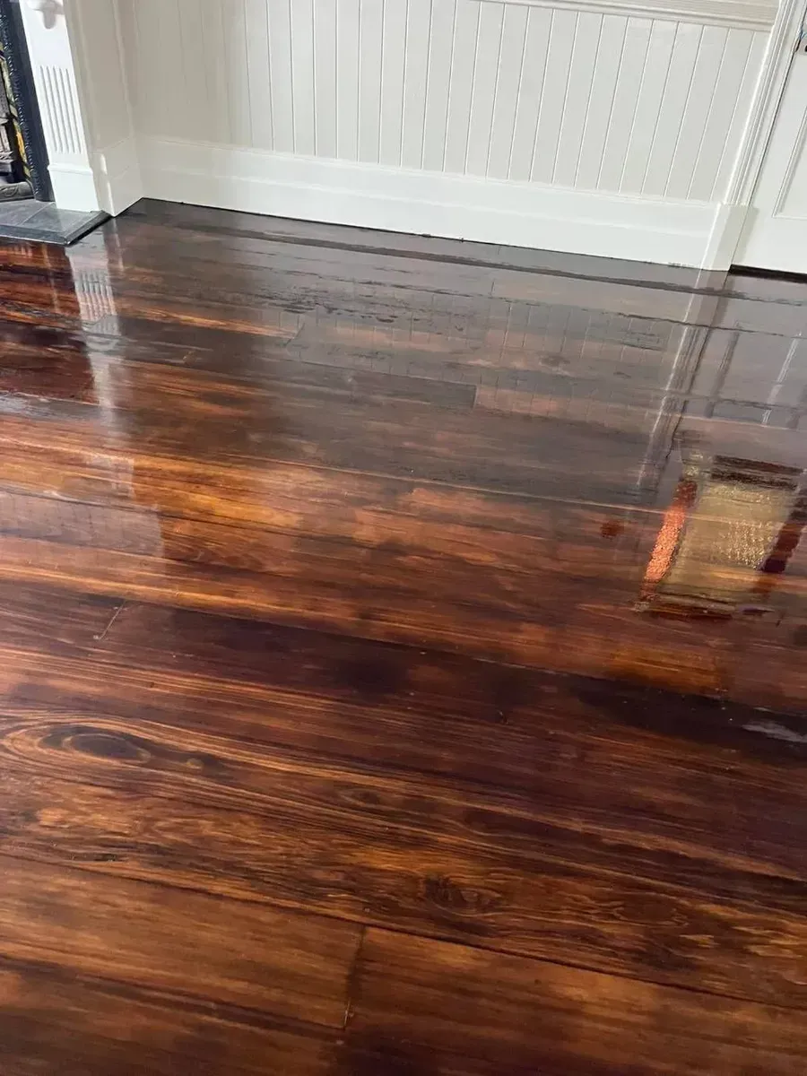 Shiny, dark brown hardwood floor reflecting light, against a white wall and trim.  — Toowoomba Polished Floors in Oakey, QLD