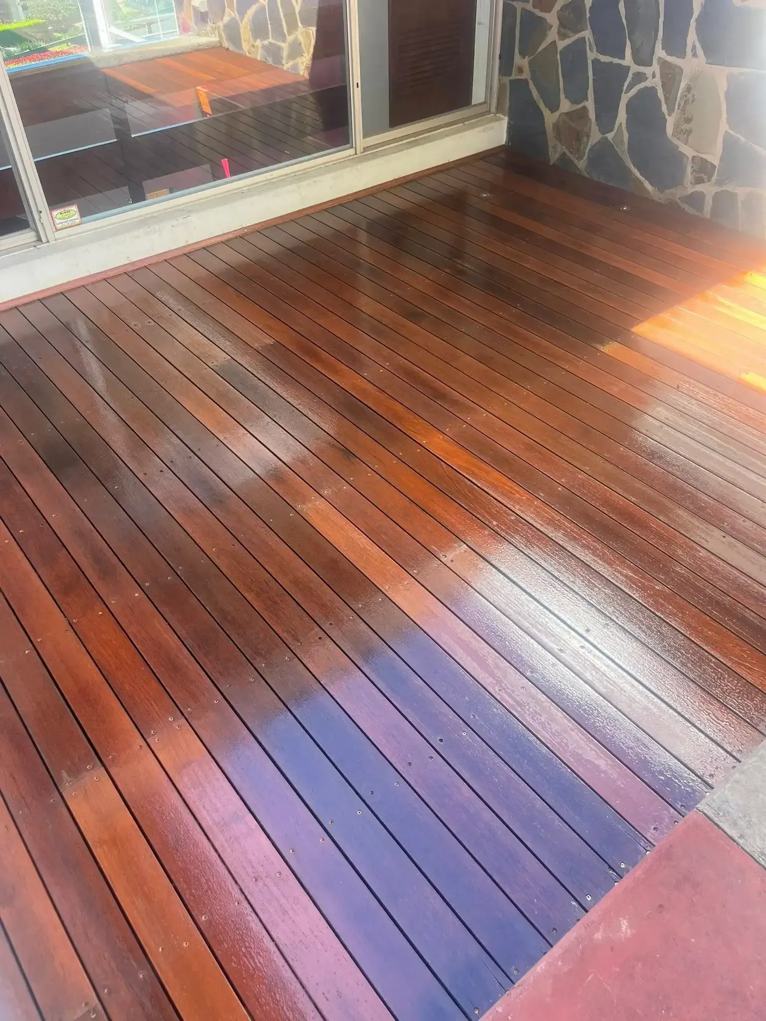 Wooden deck partially stained, with wet, shiny planks. Dark brown wood. — Toowoomba Polished Floors in Dalby, QLD