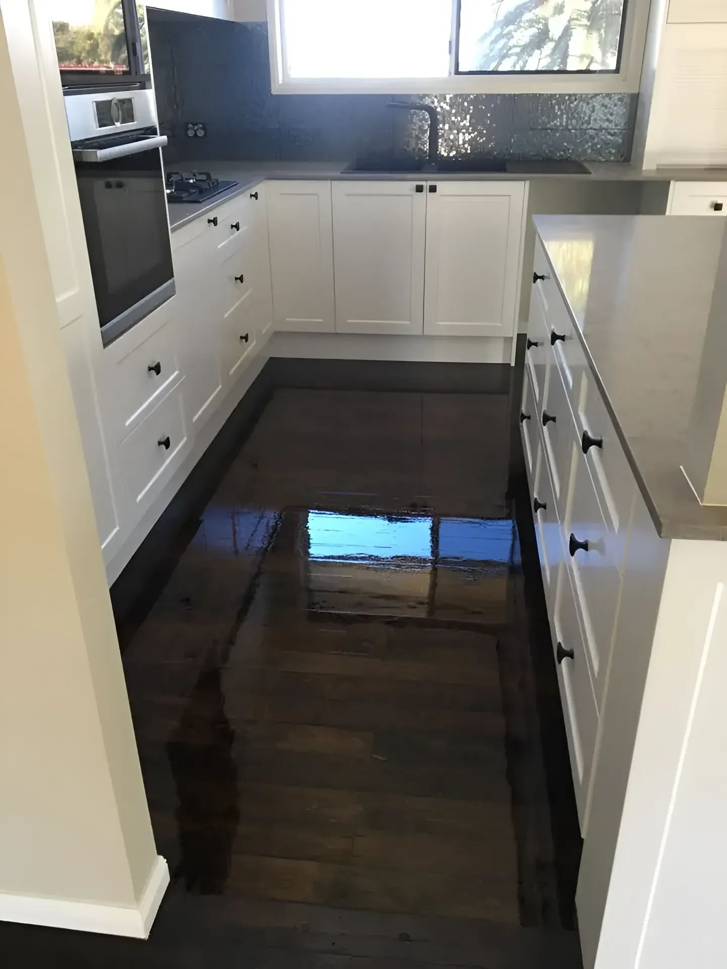 White Kitchen with Dark Wood Floors and Grey Countertops — Toowoomba Polished Floors in Pittsworth, QLD