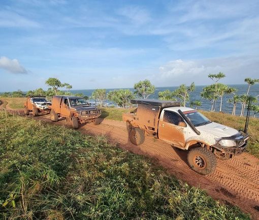 A Group Of Trucks Are Driving Down A Dirt Road — 4x4 Specialist in Townsville, QLD