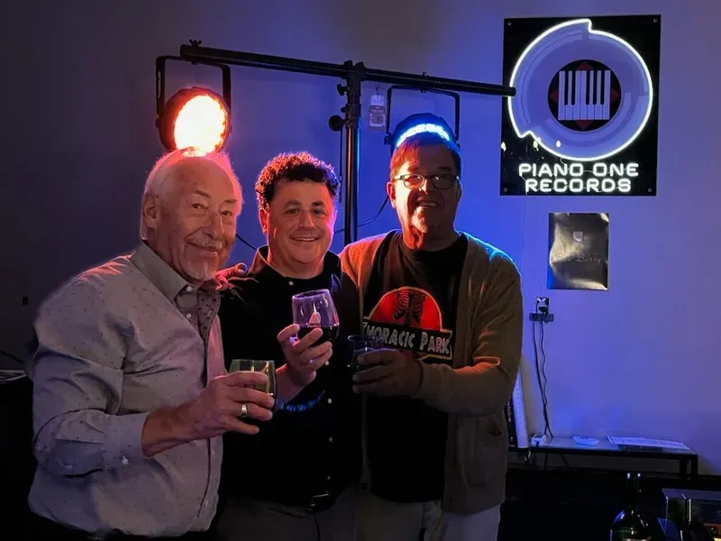 three men standing in front of a piano one records sign