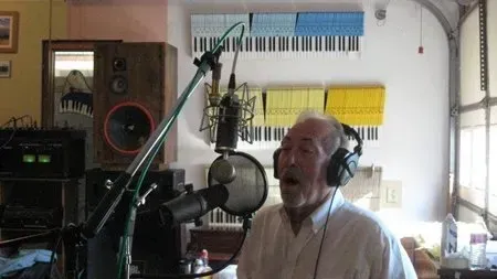 Bob Barry wearing headphones is singing into a microphone in a studio