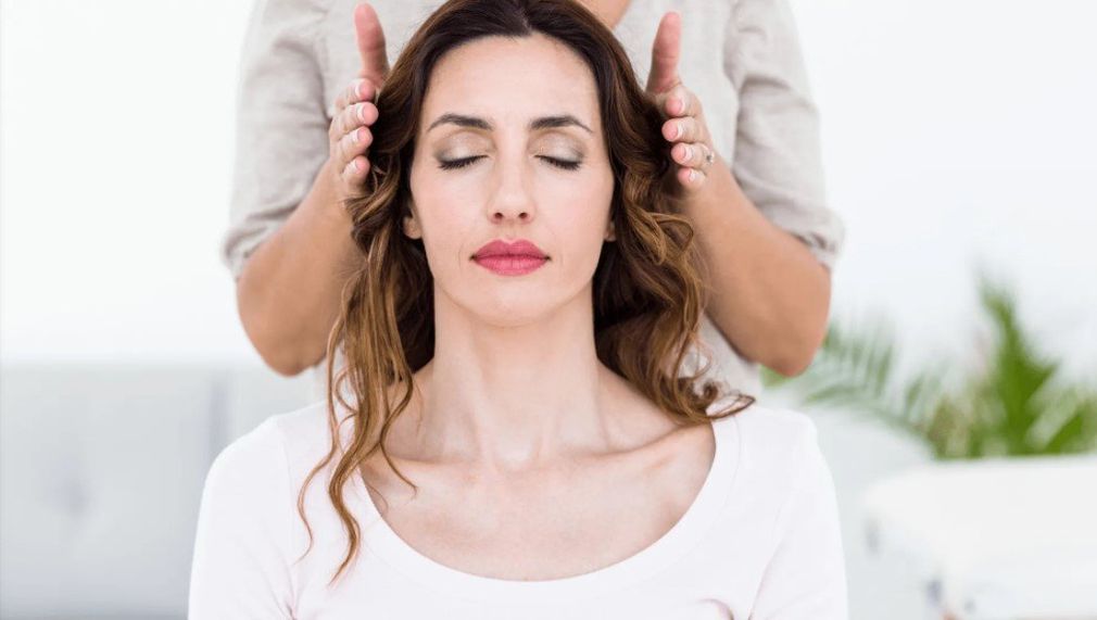 reiki of Austin reiki master healing woman with hands by head while sitting