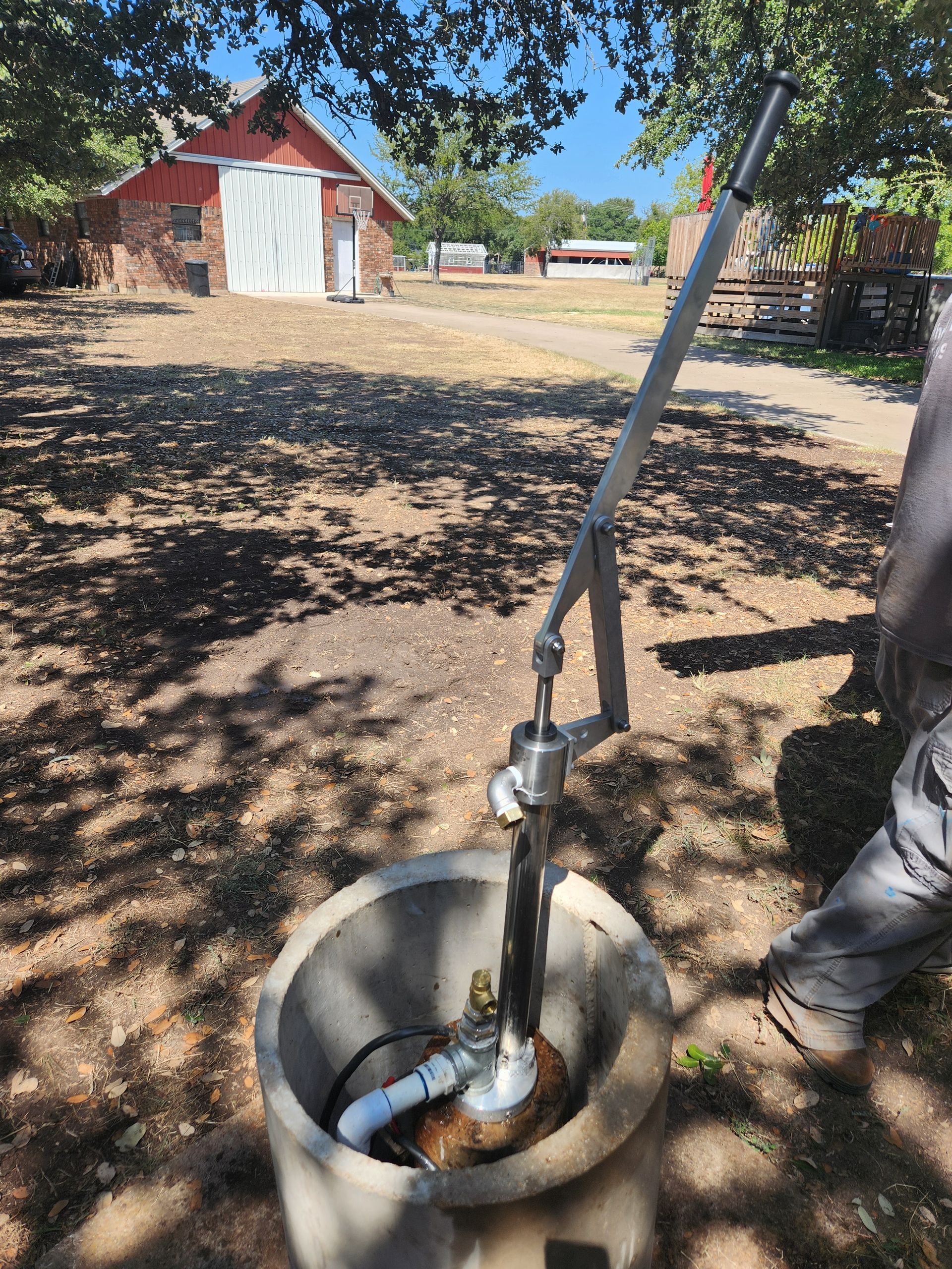 A person is using a hand pump to pump water from a well.
