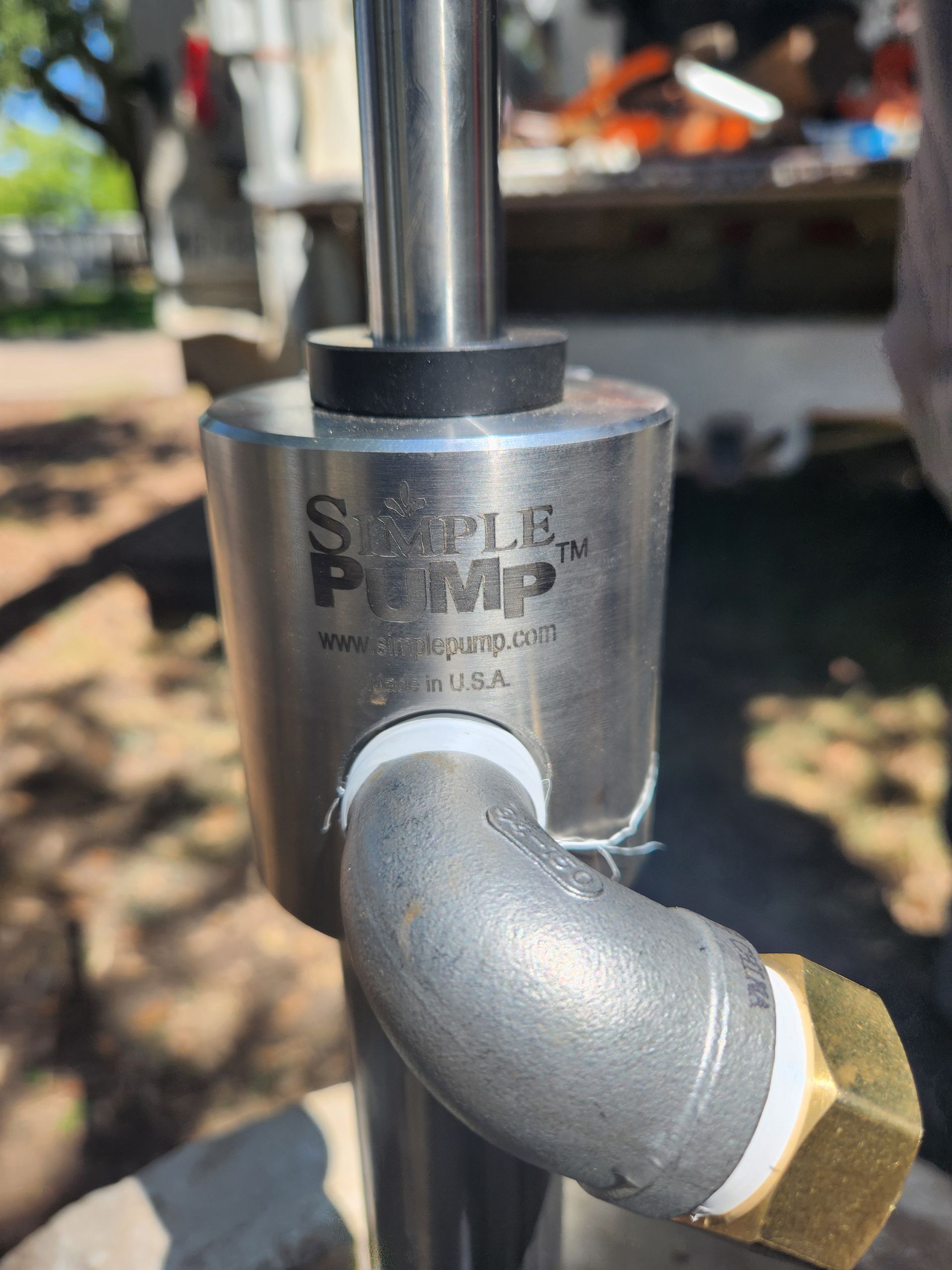 A close up of a stainless steel pipe with a hose attached to it.