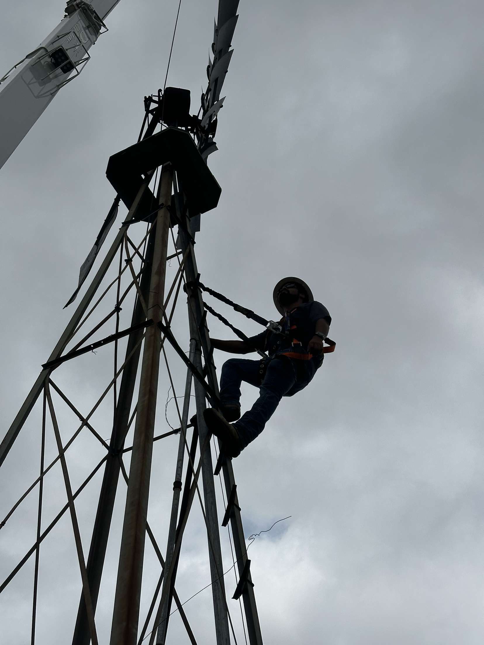 A man is climbing up a very tall pole