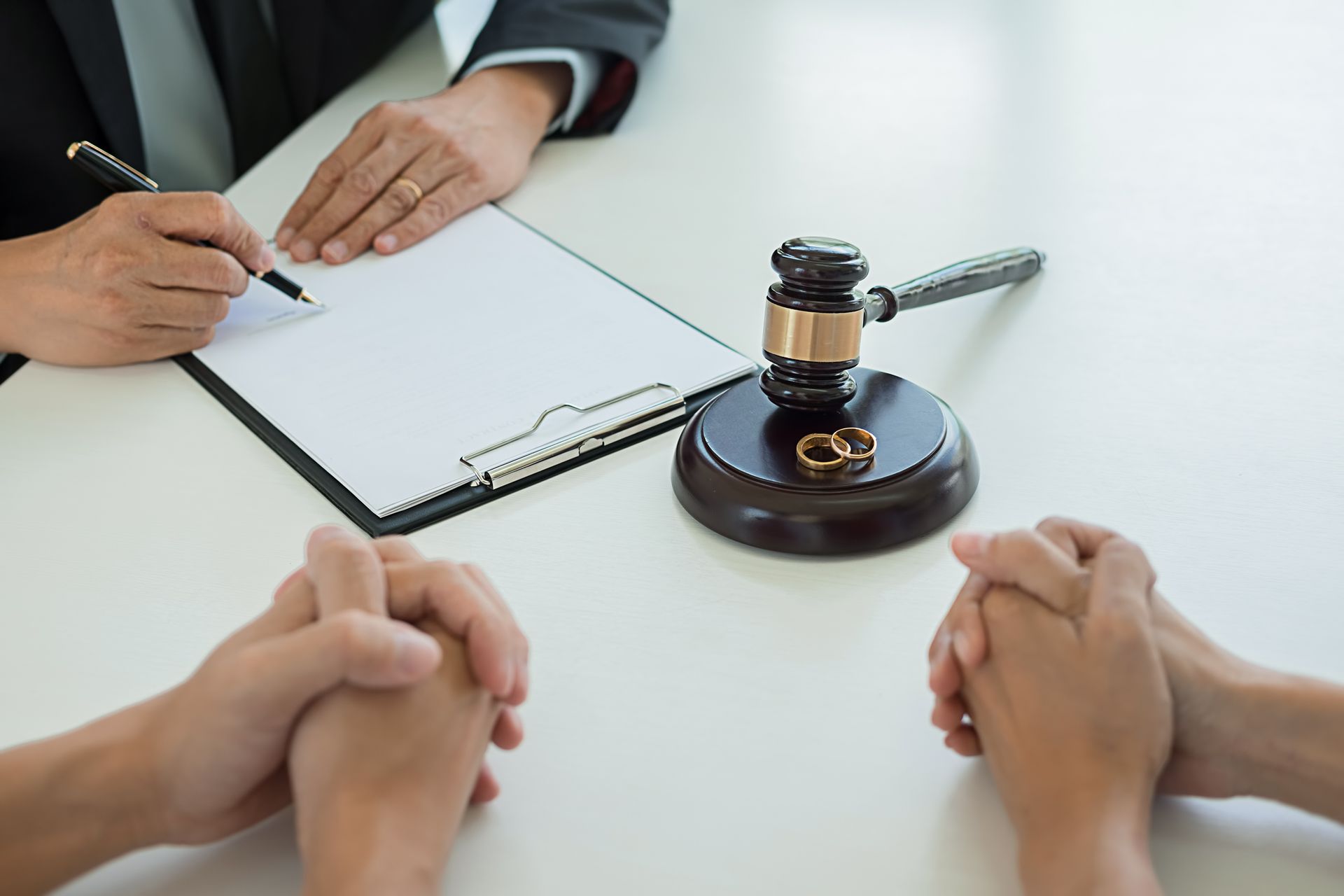 A couple is sitting at a table with a judge 's gavel and a clipboard.