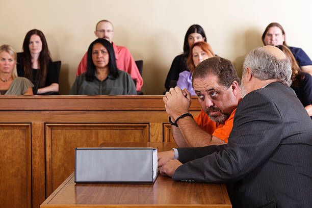 A man is sitting at a table in front of a judge in a courtroom.