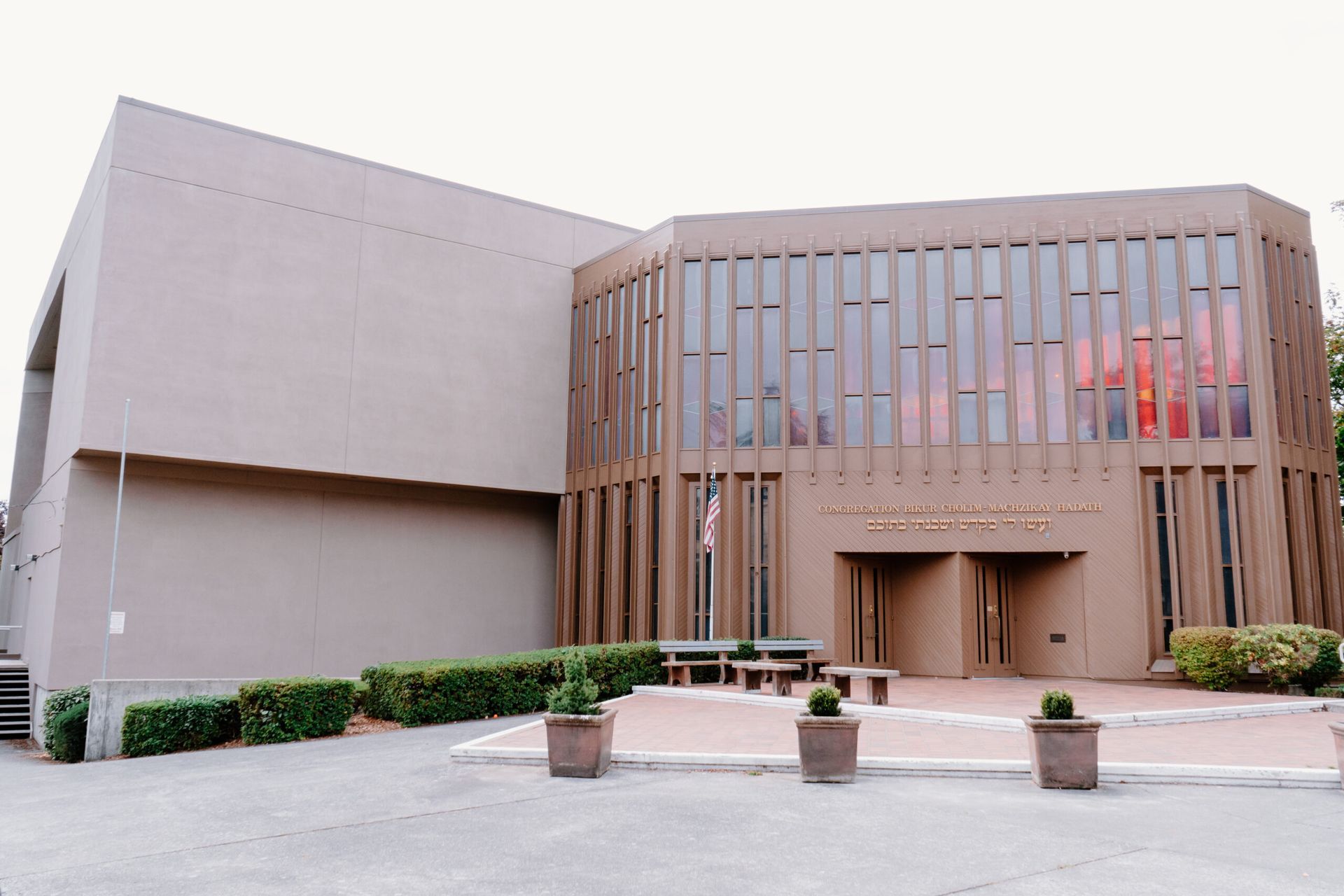 A large building with a lot of windows is surrounded by bushes and potted plants.