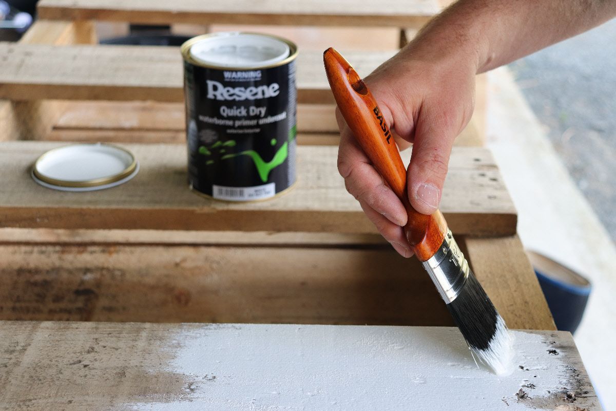 A person is painting a piece of wood with a brush.