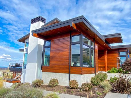 A modern house with a lot of windows and a chimney.