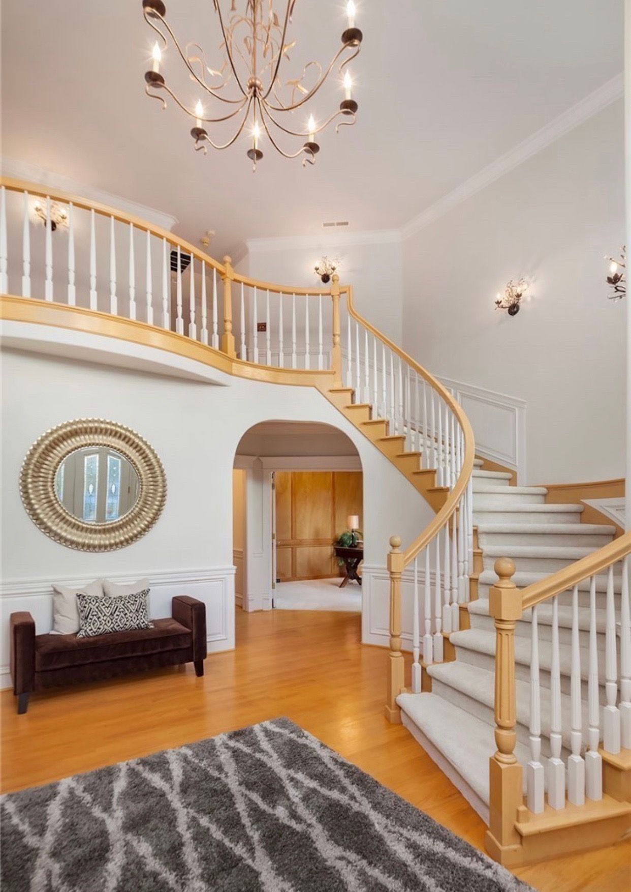 A large hallway with a curved staircase and a chandelier.