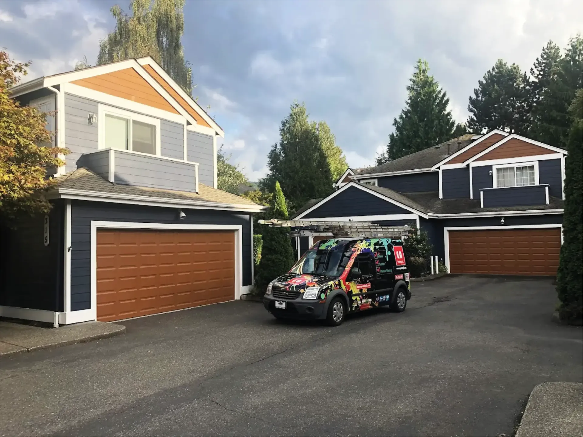 A van is parked in front of a house with two garage doors.