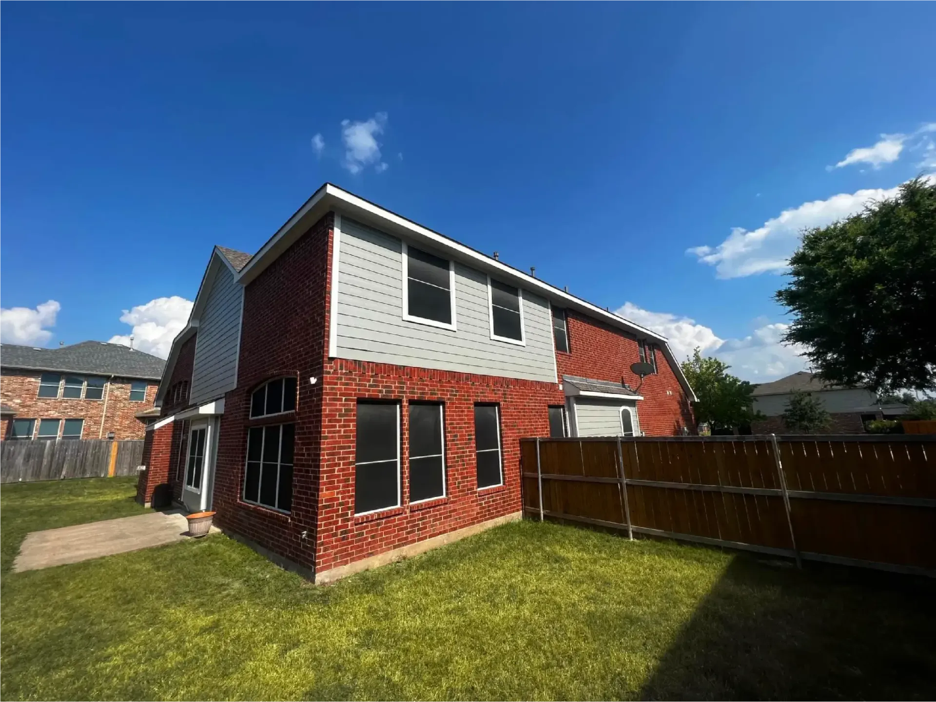 A brick house with a wooden fence in front of it.