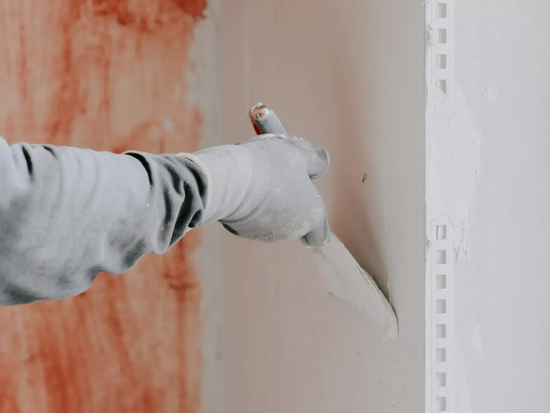A person is plastering a wall with a spatula.