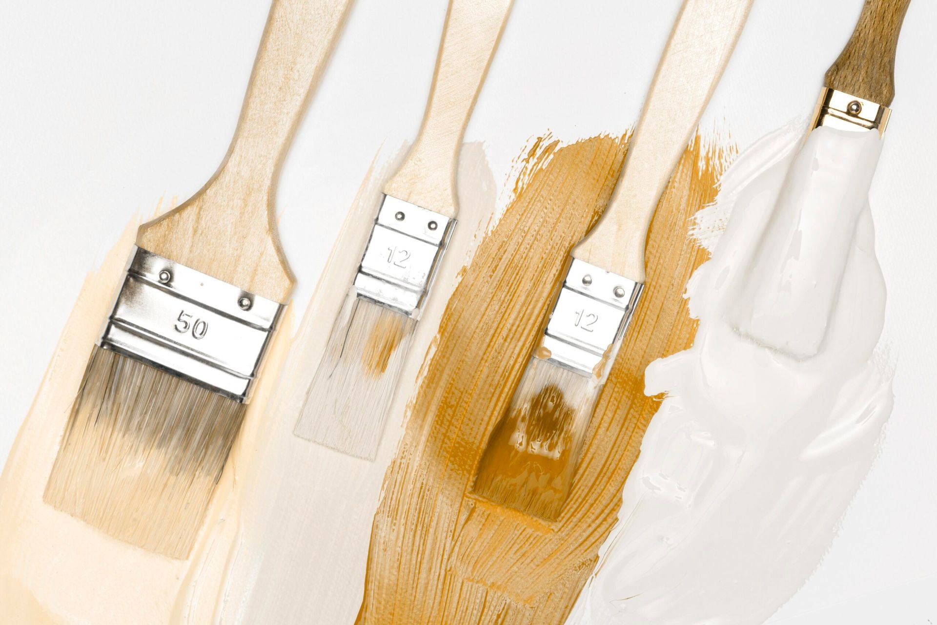 Three paint brushes are sitting next to each other on a white surface.