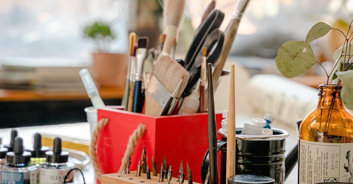 A red box filled with brushes and scissors is sitting on a table.