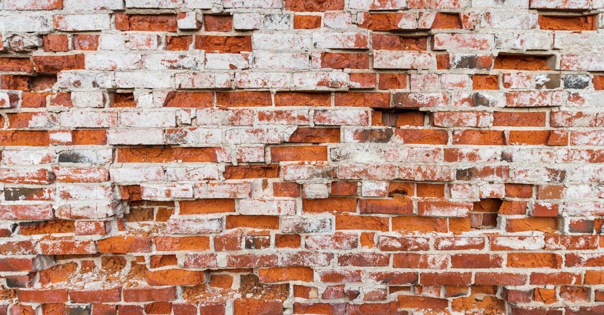 A close up of a brick wall with white paint peeling off of it.