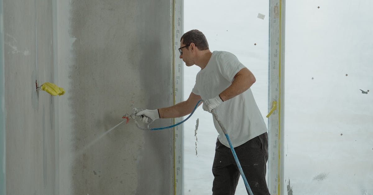 A man is spraying a wall with a hose.