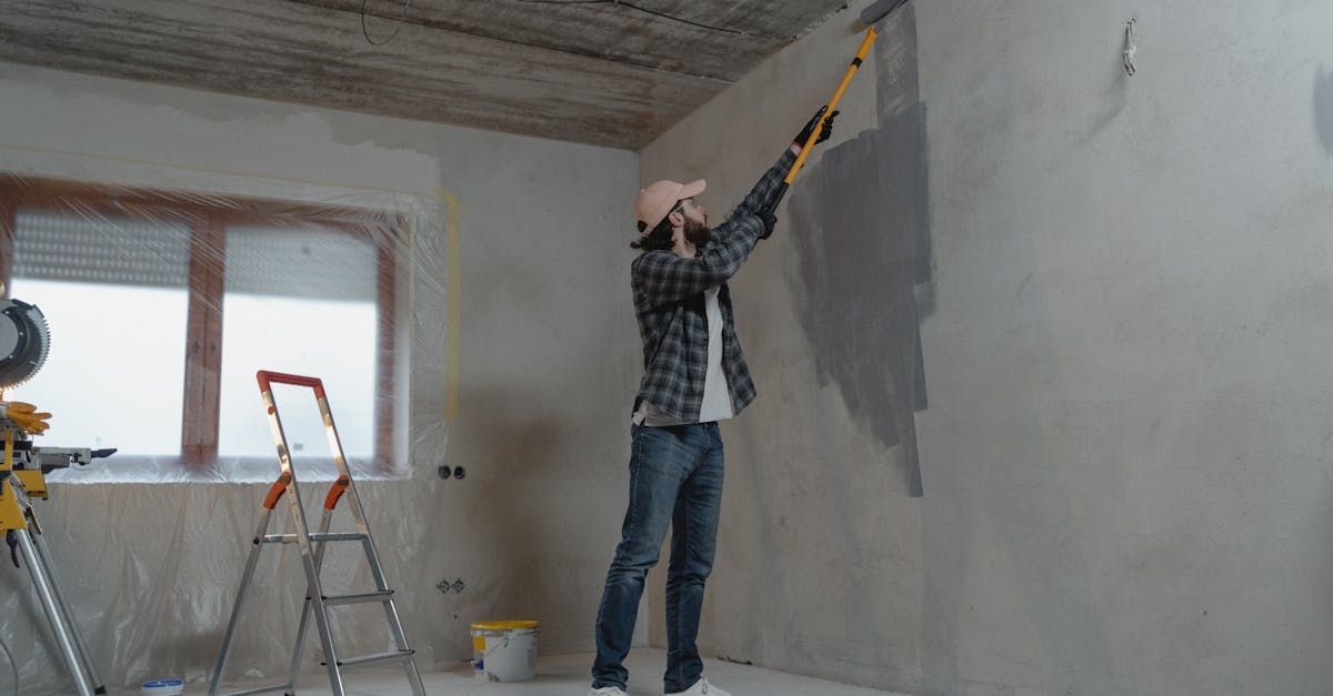 A man is measuring a wall with a level in a room.