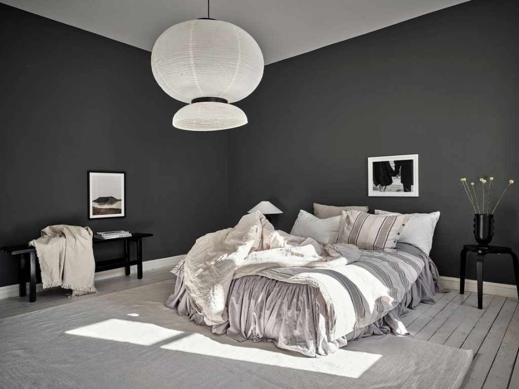 A bedroom with black walls and a bed with white sheets and pillows.