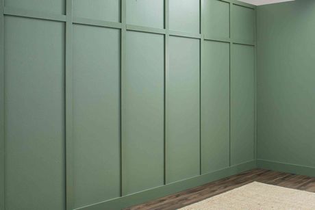 A room with green walls and a rug on the floor.