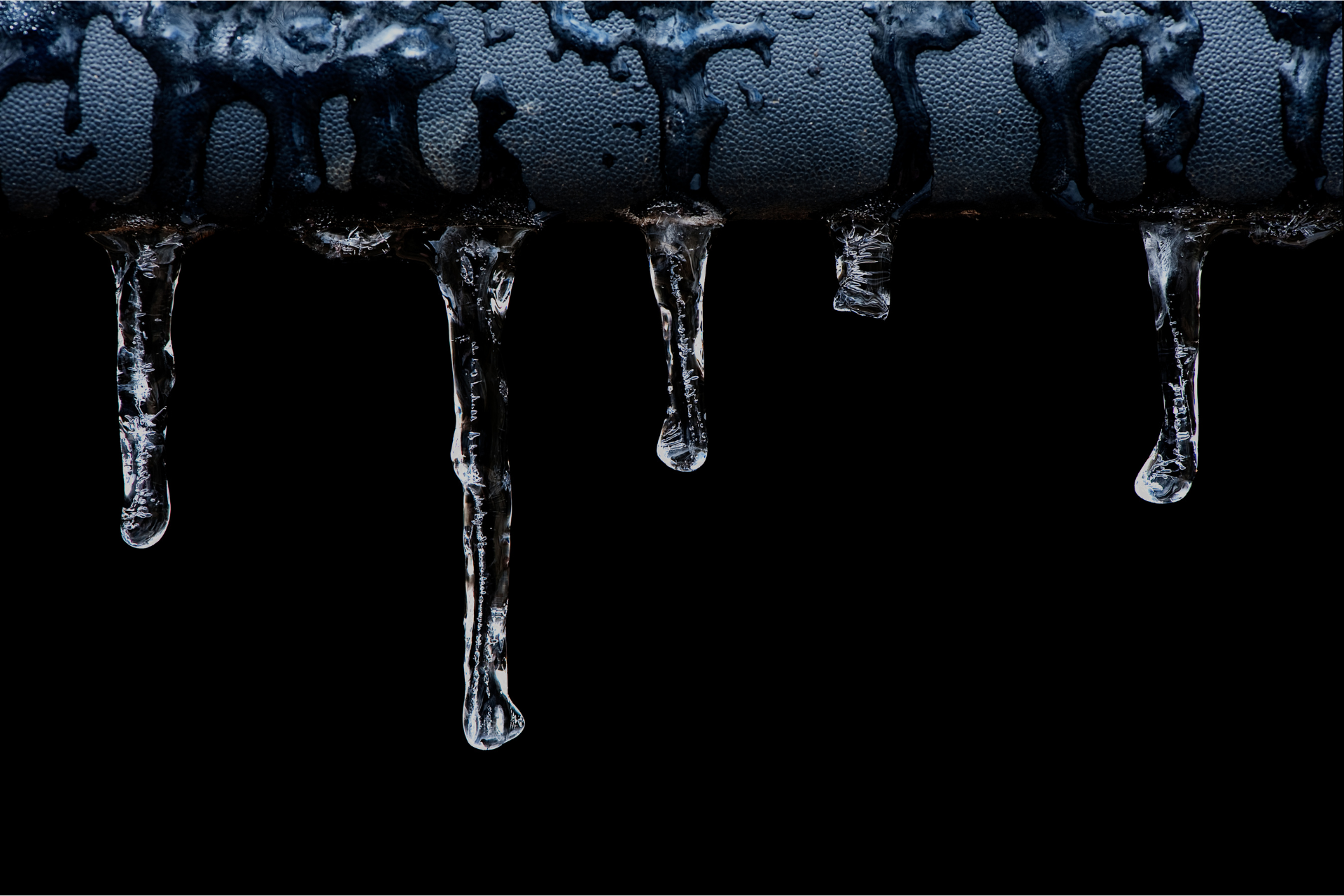 icicles are dripping from a pipe on a black background .
