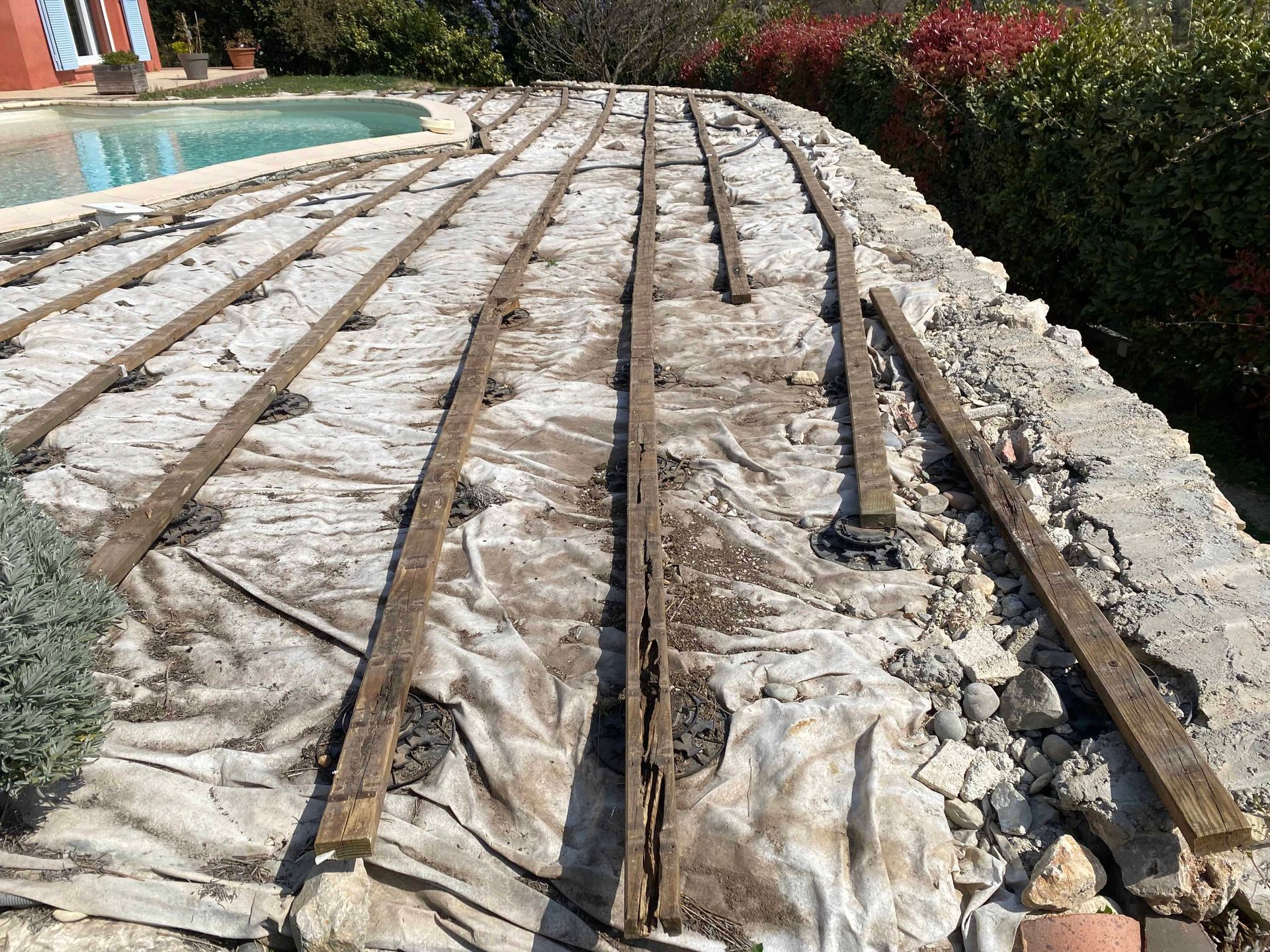 Une terrasse en bois est en cours de construction à côté d'une piscine.