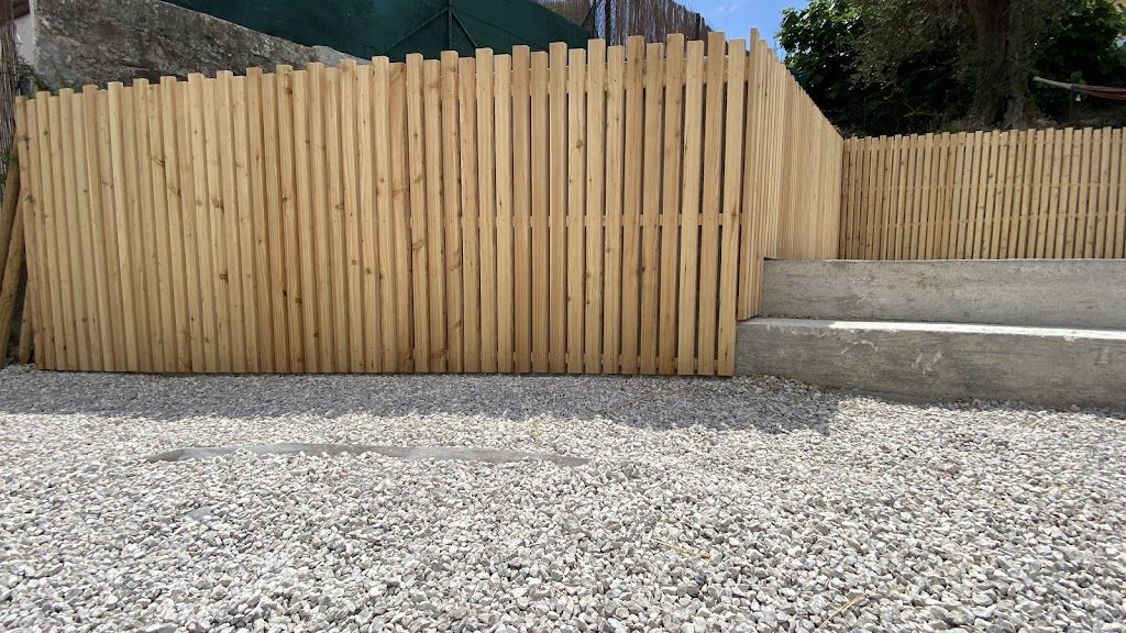 Une clôture en bois est posée sur une allée de gravier.