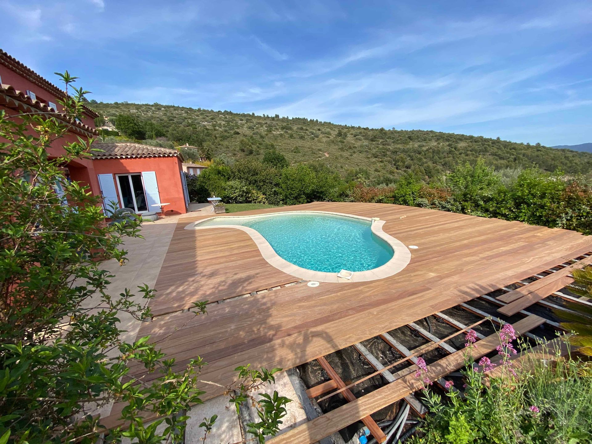 Une grande piscine est entourée d'une terrasse en bois.