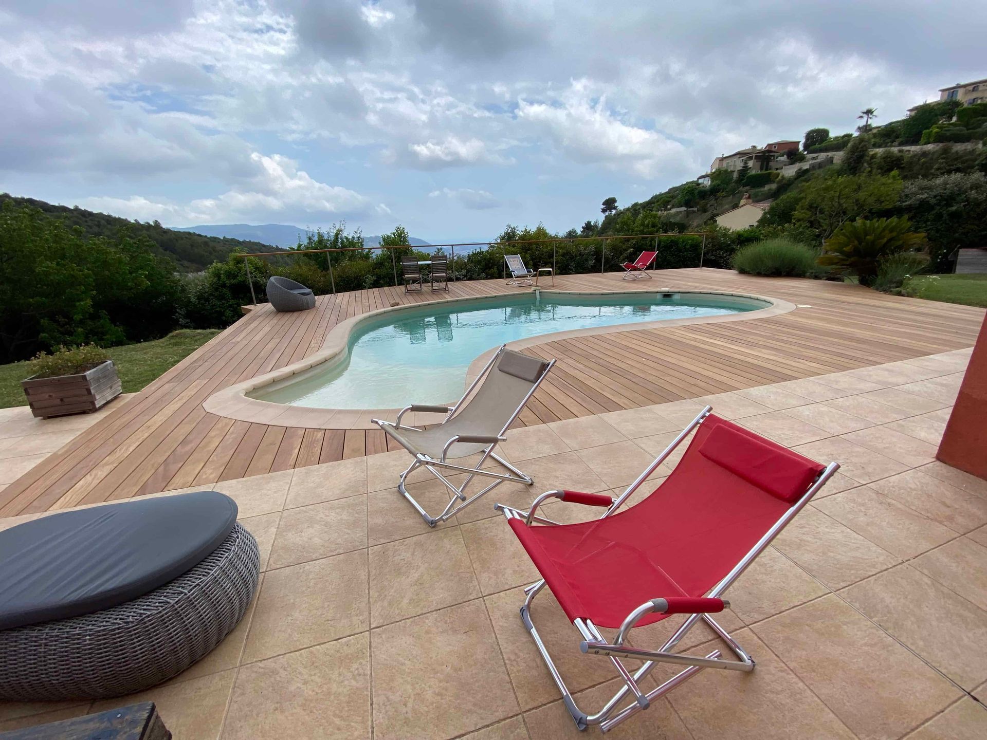Deux chaises pliantes rouges sont assises sur une terrasse à côté d'une piscine.
